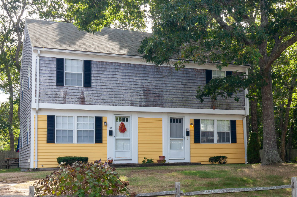 Colonial-style duplex with a yellow front wall